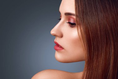 İnsanlar, güzellik kavramı. Çıplak esmer kadın, harika makyaj yana portresi, kırmızı boyalı dudaklar, sağlıklı saf deri, pozlar karanlık studio çerçevede, aşağı düşünceli görünüme sahip.