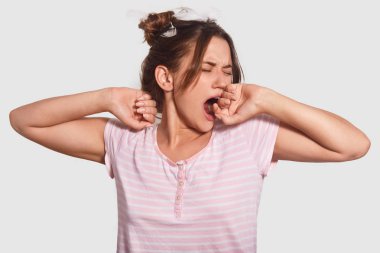 Onun yüksek zaman yatakta gitmek! Uykulu genç kadın kükrüyor, ifade yorgun, yatmak istiyor, nightclothes içinde giyinmiş, beyaz arka plan üzerinde izole, Aile içi atmosfer sahiptir. Geri kalan kavramı.