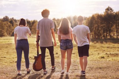 Gençlerin açık shot sırt için kamera standı, sahada, recreat kullanım gitar için hareket halinde fotoğraflandı edilmektedir şarkıları söyleyerek, yaz tatilinde yürüyüşler. Gençlik, dinlenme ve yaşam tarzı kavramı