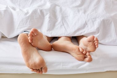 Tembel gün kavramı. Beyaz battaniye metreden çıplak hanımları ve kocalar. Dişi ve erkek yatakta kalmak, ayak üzerinde odaklanmak, hafta sonu ve beraberlik keyfini çıkarın, uzun süre uyku. İnsanlar, dinlenmek ve rahatlamak kavramı