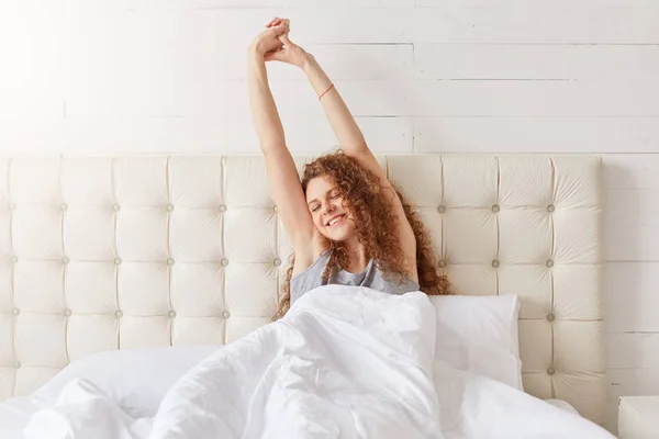 Beautiful Curly Delighted Young Female Wakes Good Mood Stretches Bedroom — Stock Photo, Image
