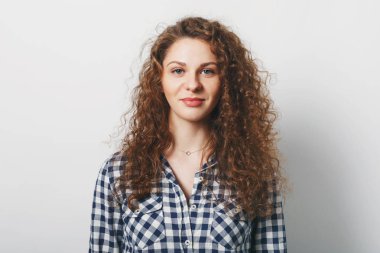 Bel muhteşem erkek portresi kadar rahat, beyaz arka plan üzerinde izole giyinmiş kıvırcık saç modeli vardır. Güzel kadının sağlıklı cilt ve çekici görünüm ile bir şey memnun var. Yüz ifadesi