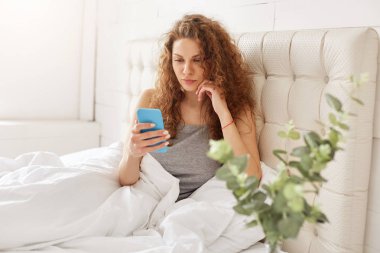 Pijama, Sevimli genç kadın modern akıllı telefon tutar, e-posta formu arkadaş yatak odası, kablosuz internet bağlantısı bağlı dikkatle mobil uygulaması üzerinde boş zaman harcıyor yatak odasında okur