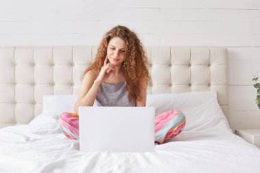 Pijama kaygısız erkek portresi çapraz bacakları yatakta oturur, dizüstü bilgisayarda ilginç film izlemekten zevk alan, hafta sonu evde geçirir. Kadın surfes sosyal ağlar yatak odasında