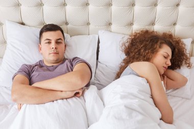 Yakışıklı brunet erkek portresi geçti ellerini tutar, rahat yatakta yatan kız yakınındaki yatıyor. Aile çift yatak odasında olsun. İnsanlar, yaşam tarzı, uyku ve dinlenme kavramı