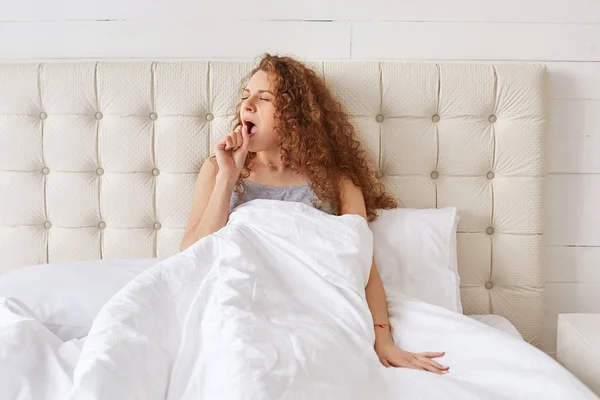 Portrait Beautiful Curly Lovely Woman Yawns Bedroom Comfortable Bed Sits — Stock Photo, Image