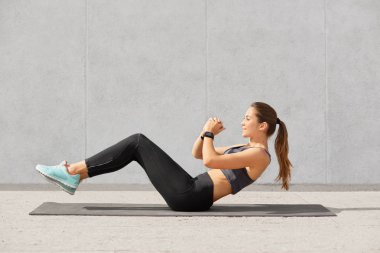 Kendini at kuyruğu ile sportif kadın kararlı, tozluk, top, spor ayakkabıları, smartwatch basın dağda giyinmiş, kas vücut sahip olmak istiyor, spor salonunda egzersiz vardır. İnsanlar, spor salonu ve spor kavramı.