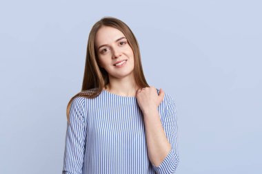 Karanlık ahir, hoş çekici gülümseme ve görünüm, oldukça güzel genç kadın portresi şık bluz giyer, mavi arka planı tek başına durur. Olumlu duygular ve insanlar kavramı