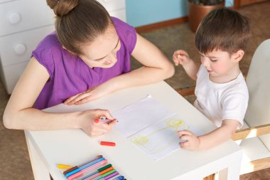 Üstten görünüm akıllı yetenekli küçük çocuğun araba kağıt üzerinde renkli işareti kalemle çizer, farklı resimler yapmak için sever, sevgi annesi ile zaman harcıyor. Çocuk ve geliştirme kavramı
