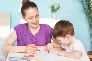 Görüntü oluşturma ile meşgul olmak boş kağıda, resim çizer, renkli işaretleyicileri kullanabilirsiniz, erken yaşından itibaren sanat anlayışı geliştirmek çalışır onun küçük oğlu yakınındaki çekici kadın anne oturur