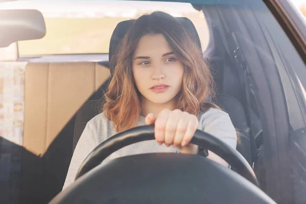 照片中有魅力的女司机坐在车里 教书开车 缺乏经验 有深思熟虑的表情 交通堵塞的妇女 在长途旅行中思考某事 — 图库照片