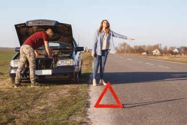 Araçlar yolda gibi yardıma ihtiyacı var, kocası ile birlikte araba ile seyahat ve hasar ile motor, umutsuz kadın durakları cant çözmek problem tek başlarına, kırmızı uyarı üçgeni ön planda.