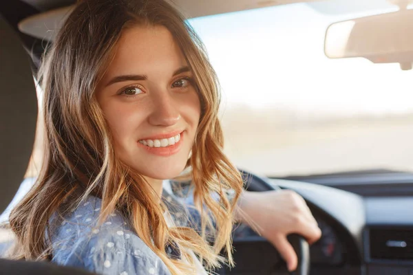 看着漂亮笑容的女人带着宽阔的笑容 有诱人的神色 坐在车轮的车上 经过长途旅行后 直视摄像机 正面妇女驾驶汽车 享受速度 — 图库照片