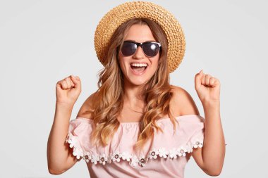 Kapalı atış başarılı çok memnun kadın modeli diş clenches, yaz tatili, yurtdışına seyahat hazır sevinir, hasır şapka, bluz, beyaz arka plan üzerinde izole giyer. Peope, yaşam tarzı, zafer