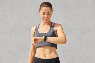 Shot fitness Bayan veya jogger dikkatle akıllı saatine bakar, nabız denetler ve kalori sayar, sağlıklı bir yaşam tarzı vardır, spor için düzenli olarak, rahat tanktop, gösterir mükemmel şekilde giyinmiş giriyor
