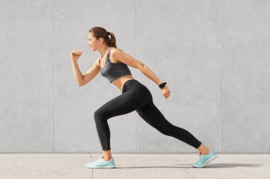 Yatay atış sportif gövdeli esnek kadının poz, maraton, sportsclothes, gri beton duvardan izole giymiş başlamak için hazır duruyor. İnsanlar. spor, belirlenmesi kavramı.