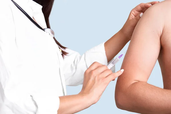 近距离拍摄女性医生的手使 Vacciantion 使用注射器 在上臂注射 防止严重疾病 孤立在蓝色背景 选择性对焦 保健理念 — 图库照片