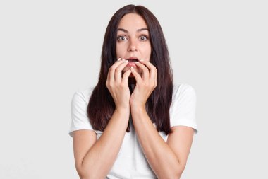 OMG, onun korkunç! Korkmuş yüz ifadesi ile şok endişeli kadın el ağız yakın tutar, duyar şok edici haberler, giyer beyaz casual t sshirt, exxpresses beklenmedik duygular, kötü duygular