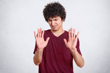 Memnun genç dur jest gösterir, değil rahatsız ona sorar, avuç içi önünde duruyor, beyaz arka plan üzerinde izole rahat t gömlek giymiş bir şey gibi değil. Adam nefret hareketleri kapalı hisseder
