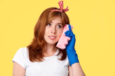 Tüm odalarda, kullanır sünger olarak cep telefonu, temizlendikten sonra meşgul ev hanımı foolishes arkadaşıyla konuşuyor gibi yapıyor, yurtiçi iş ve ev işleri, giyer şık kafa bandı ve beyaz casual t gömlek görüşmek