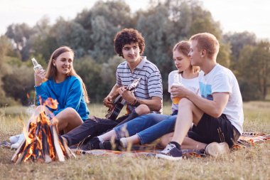Yatay atış samimi gençlerin neşeli ifadeler var, hafta sonu bir araya sırasında boş vakit geçirmek, kamp ateşi oturmak, gitar, içki içecek için şarkılar, birbirleri ile iletişim.