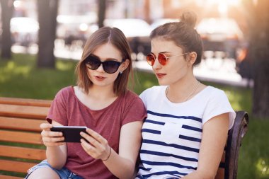 Genç kız tonları olarak yatay görünüm online yolu ile hücre telefon, kablosuz internet'e bağlı tutorail video izle, bankta poz, kapalı dinlenme saati ve günü zevk, iyi ilişkileri var