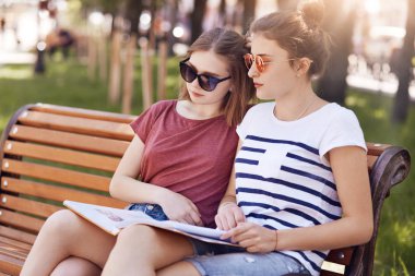 Kadın sınıf sit yakından her diğer, tahta bankta oturup iken bir defterinden bilgi okumak için ifadeler, kayıtsızca giyinmiş odaklı. Yaklaşan final sınavı açık için öğrencileri hazırlamak.