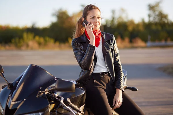 Jonge Vrouwelijke Biker Met Ernstige Expressie Telefoongesprek Cellulaire Heeft Draagt — Stockfoto