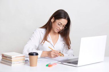 Kadın blogger gözlük yuvarlak beyaz gömlek giyer, Not Defteri'nde yazıyor, dizüstü bilgisayarda çalışır, kahve, webiste geliştirme ile meşgul içecekler, üzerinde beyaz izole kablosuz Interent bağlantıyı kullanır