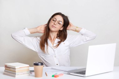 Yorgun kadın iş yerinde uzanıyor, beyaz gömlek ve gözlük takıyor, overworked hissediyor, önünde açılan dizüstü oturur, yenilenmiş, hissetmek paket servisi olan restoran kahve beyaz arka plan üzerinde izole içecekler