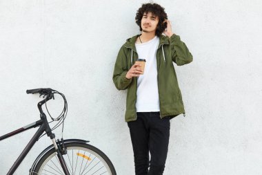 Düşünceli erkek el baş, çizikler kafasında şaşkınlık içinde tutar, karar vermek çalışır, paket servisi olan restoran kahve tutar, moda ceket giyer, beyaz arka plan üzerinde izole bisiklet sürmek.