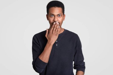 Kapalı atış yakışıklı Afro man surprisement ağzıyla kapsar, içinde surprisement diye bağırıyor, gözleri dışarı çıktı Amerikan şaşkın, beyaz arka plan üzerinde izole rahat kıyafetler giymek. OMG kavramı