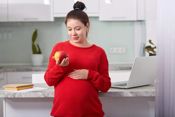 Photo Pregnant Woman Eats Fruit Enrich Vitamins Dressed Red Sweater — Stock Photo, Image