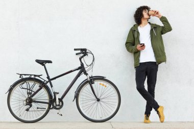 Yatay moda genç kadeh geçti ellerini tutar, cep telefonu tutan, metin mesajı gönderir, paket servisi olan restoran kahve içer, spor bisiklet, beyaz duvardan izole yakınındaki teşkil etmektedir. Yaşam tarzı kavramı