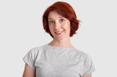 Kısa saç modeli, kadınla attactive yakışıklı beyaz arka plan üzerinde izole sıradan gri t gömlek giymiş geniş gülümseme yakaladı. Güzel zencefil kız arkadaşı modelleri kapalı portresi. Olumlu duygular