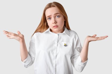 Clueless kız shruggs omuz üzgün, kızgın yüz ifadesi olan, kararı, beyaz arka plan üzerinde izole karışacak kamera, şık gömlek giyer bakar veremem. Habersiz genç kapalı