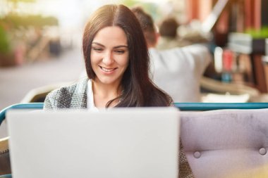 Pozitif Avrupa kadın dişlek gülümseme vardır, dijital netbook çalışır, açık hava kafe rahat kanepe oturur, iyi günler, surfes sosyal ağlar Kablosuz internet'e bağlı sahiptir. Boş zaman kavramı