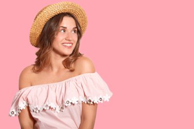 Stüdyo shot olan Avrupa görünüm, hoş görünümlü kadın bir kenara görünüyor, güzel gülüş sende..., şapka ve terfi için boş alan ile pembe duvarın üzerinden izole şık bluz giyer