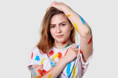 Yakın atış çekici genç kadın sanatçı, giyim boya ile renkli çizimler yaptıktan sonra lekeli, ciddi bakışları have beyaz arka plan üzerinde izole. Yetenek ve hobi