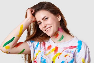 Çekici memnun Bayan stüdyo çekim el başına tutar, memnun ve ilham hissediyor, elbise ve el, art Studio beyaz arka plan üzerinde izole renkli Suluboyalar izleri vardır