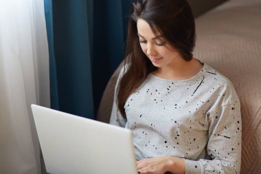 Serbest çalışan genç kadın kazak giymiş, dizüstü bilgisayarda bilgi türleri, evden çalışır, rahat oda yakın katta teşkil etmektedir, Aile içi atmosfer sahiptir. İnsan ve teknoloji kavramı