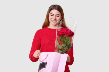 Karşılama hediyesi benim en sevdiğim şeydir. Paket, Genç Bayan açar memnun gülümseyerek çekici bir şey görür, kırmızı gül, kayıtsızca, giyinmiş ifade eder olumlu duygular üzerinde beyaz duvar izole tutar