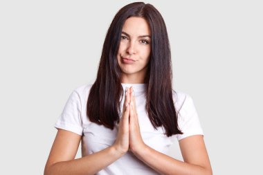 Avrupa görünüm yirmi beş yaşlarında, koyu saçlı model teşkil etmektedir harika kız yüz için tüm dikkatini olanak sağlayan izole gri arka plan üzerinde şık beyaz giysili.