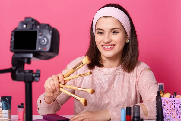 Blogging, tecnología moderna y concepto de personas. Feliz mujer sonriente belleza video blogger sostiene pinceles para el maquillaje mientras que la grabación de vídeo tutorial en casa para vlog. Joven mujer gana dinero en internet . — Foto de Stock