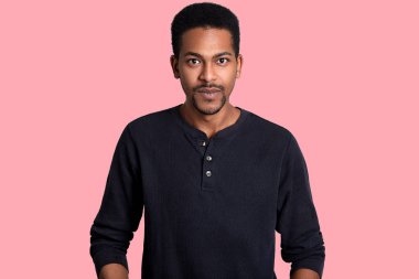 Genç yakışıklı Afrika adam stüdyo çekim pembe arka plan siyah gömlek giyer. Erkek mutlu görünüyor, onun yeni ilginç fikri yok. Studio, model pozlar kamera bakar. İnsanlar kavramı.