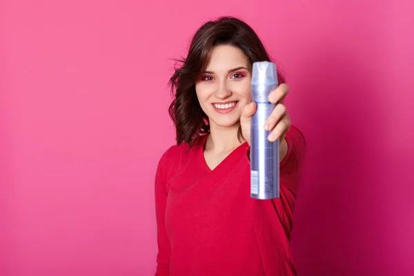 Shot de bastante joven hembra sostiene spray para el cabello, tiene expre agradable — Foto de Stock