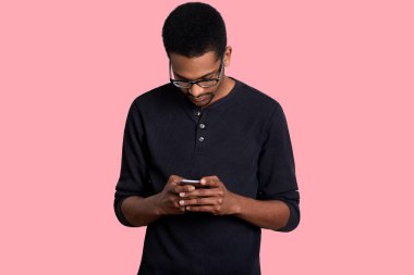 Genç siyah adam cep telefonu, smartphone cep telefonu ile sosyal medya denetimi kullanır. Yakışıklı erkek casual jumper giyer, onun aygıtı tutan, tepeden bakıyor, Internet bilgi bulur. İnsan ve teknoloji kavramı.