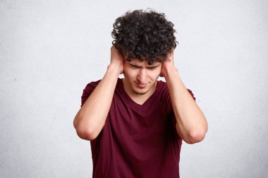 Umutsuz yorgun rahatsız Avrupa kapalı gözlü çocuk portresi ellerini kafasına koyar. Negatif insan duygu ve duygu. Siyah kıvırcık saçlı sufers karşılıksız sevgi ile yakışıklı öğrenci.