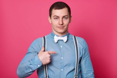 Sakin genç erkek dostu yüz expessions puanla bir kenara işaret parmağı ile reklam içerik için boş alan gösterir veya promosyon metni, kısa saç stili, pembe bir arka plan üzerinde izole.