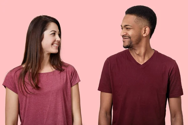 Στενή επάνω εικόνα happy νεαρό ζευγάρι ψάχνει πρόσωπο με πρόσωπο σε κάθε άλλο, χαμογελώντας, ντυμένη casual t πουκάμισα, στέκεται απολαμβάνει ο χρόνος μαζί, θέτουν απομονωμένες σε ροζ φόντο φωτογραφία στούντιο. — Φωτογραφία Αρχείου